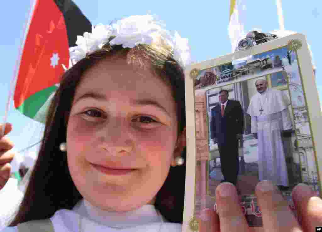 A young girl holds a photo of Pope Francis and Jordan&#39;s King Abdullah as people congregate at Amman&#39;s International Stadium to wait for the arrival of Pope Francis Amman, May 24, 2014.