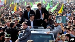 Iranian President Mahmoud Ahmadinejad, center, waves to well wishers from his car, during an annual rally commemorating the anniversary of the 1979 Islamic revolution, which toppled the late pro-U.S. Shah, Tehran, February 10, 2013.