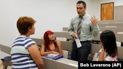 In this photo taken Wednesday Aug. 31, 2011, Tania Isabel Vazquez, left, Karen Martinez, second from left, and Miriam Garcia-Lopez, right, all 18-year-old freshman, talk with their instructor Dr. Mario Bahena.