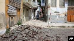 People look at the debris of a damaged building after an earthquake in the village of Plomari on the northeastern Greek island of Lesbos, June 12, 2017.