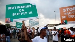 A partisan of the ruling party RDR (Rally of the republicans) holds a placard during a rally against the mutiny close to the military headquarters in Abidjan, Ivory Coast, May 13, 2017. The placard reads, "Mutinies: it's enough". 