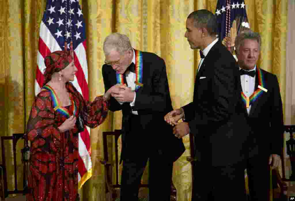 President Barack Obama watches as 2012 Kennedy Center Honors recipient David Letterman kisses the hand of Natalia Makarova during a reception for the honorees in the East Room of the White House, December 2, 2012.