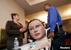 FILE - A potential applicant talks to Michelle Leonard, owner of Pittsburgh Multicultural Cosmetology Academy, at a job fair in Pittsburgh, Pa.