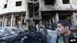 FILE - Syrian government forces inspect the damage following suicide bombings in the area of a revered Shi'ite shrine in the town of Sayyida Zeinab, on the outskirts of the capital Damascus, Jan. 31, 2016.