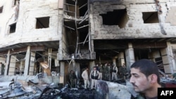 Syrian pro-government forces inspect the damage following suicide bombings in the area of a revered Shiite shrine in the town of Sayyida Zeinab, on the outskirts of the capital Damascus, Jan. 31, 2016.