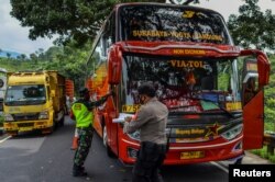 Petugas memeriksa bus pada hari pertama larangan mudik lewat laut, darat, udara, dan kereta api menjelang lebaran, dalam upaya mencegah penularan COVID-19, 6 Mei 2021, (Antara Foto / Adeng Bustomi / via Reuters.)