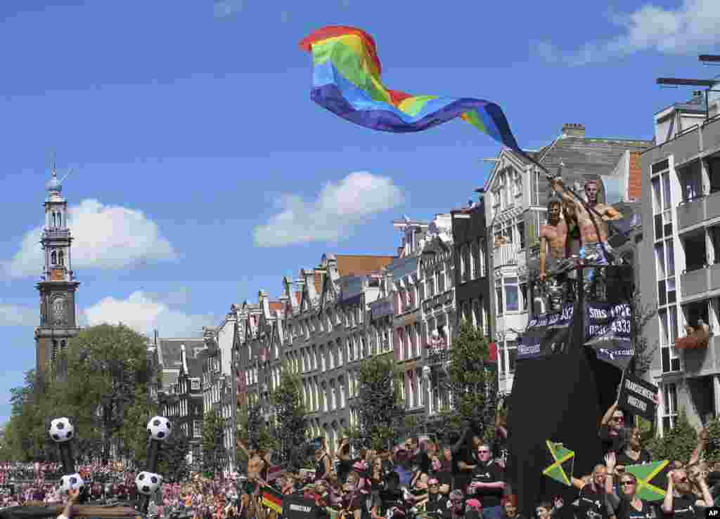 A man waves a rainbow flag during the annual Canal Parade at Prinsengracht in Amsterdam, the Netherlands. Rainbow flags are flying from scores of buildings as tens of thousands of festival-goers, many dressed in pink or wearing studded leather, party it up at one of the city&#39;s biggest events: the annual Gay Pride celebration.&nbsp;