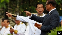 Cambodia's Prime Minister Hun Sen, second from right, talks with Sar Kheng, right, deputy prime minister and minister of Ministry of Interior, as they wait to attend the Independence Day celebrations in Phnom Penh, Cambodia, Thursday, Nov. 9, 2017. Some hundreds of civil servants and students gathered to mark the country's 64th Independence Day. The country gained independence from France on Nov. 9, 1953. (AP Photo/Heng Sinith)