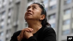 A woman prays during an outdoor Mass service, held outside Saint James Apostle Parish, because the church building suffered some damage during the 7.1-magnitude earthquake, in the Plaza de las Tres Culturas in Tlatelolco, Mexico City, Sept. 24, 2017.