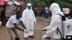 Health workers wash their hands after taking a blood specimen from a child to test for the Ebola virus.