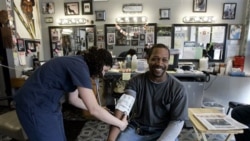 Dwight Woods has his blood pressure checked by Meghan Welsh at Flotrin's Barber Shop in St. Louis in this file photo