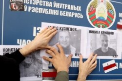 FILE - Demonstrators paste photos of opposition supporters killed during the post-election protests on the Okrestina prison wall during a rally demanding to free jailed activists of the opposition in Minsk, Oct. 4, 2020.