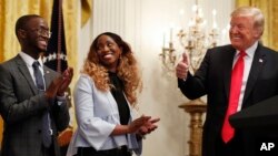 President Donald Trump, right, gives the thumbs up to Cam'eron Hill, left, and his mother LaSonya Hill, of Jacksonville, Fla., during an event about taxes, June 29, 2018, in the East Room of the White House in Washington.