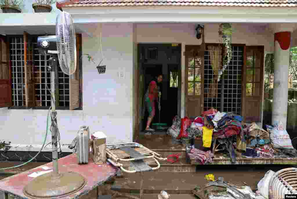 A woman cleans the mud from the entrance of her house following floods in Paravur in the southern state of Kerala, India.