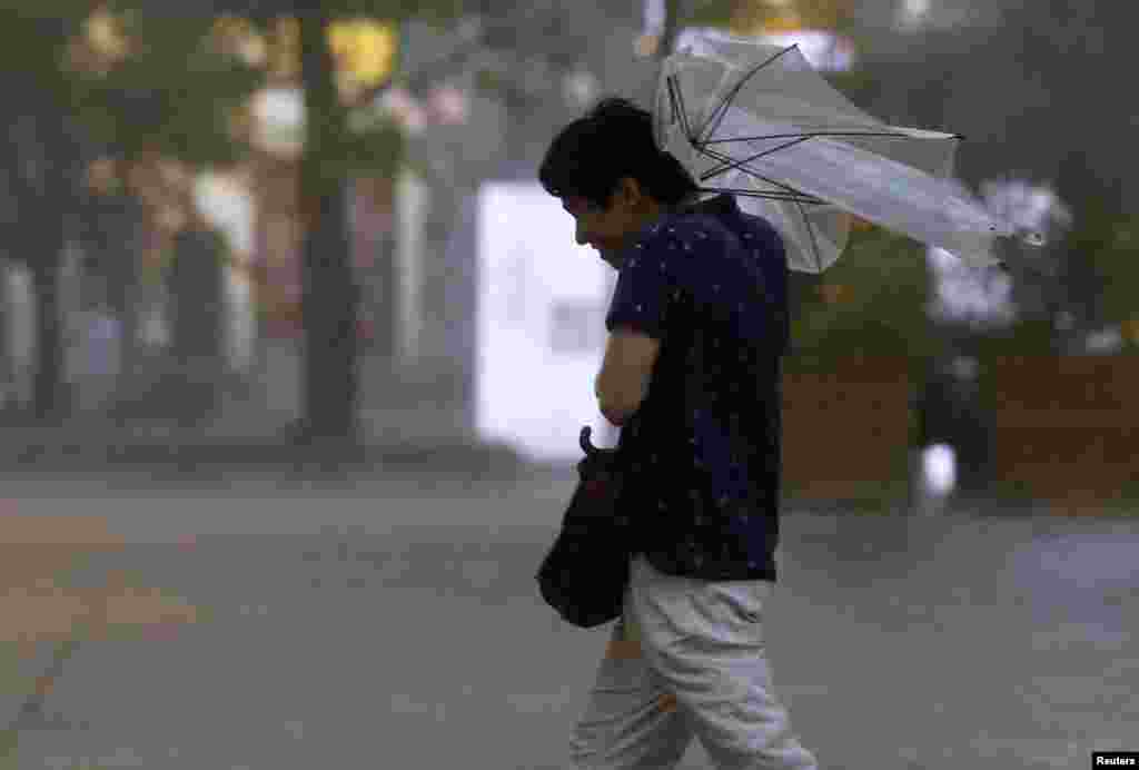 A man struggles with an umbrella in strong winds and rain caused by Typhoon Halong in Tokyo, Japan, Aug. 10, 2014.