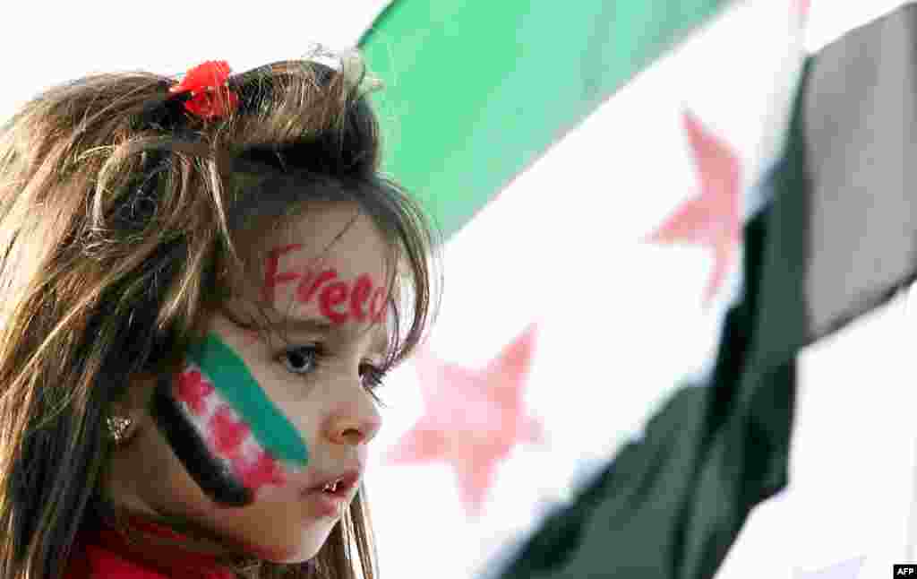 A girl has her face painted with the new revolution flag at a protest in Doha. (AP)