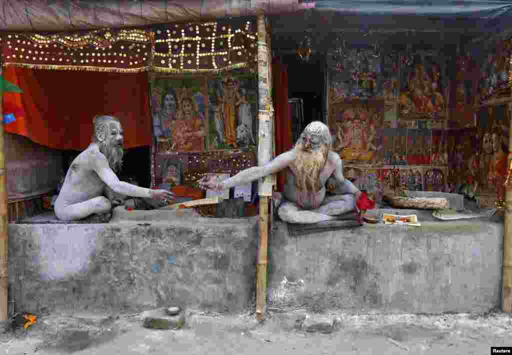 Naga Sadhus or Hindu holy men, smeared with ash, pass on a chillum to smoke inside their makeshift camps near the confluence of the river Ganges and the Bay of Bengal, ahead of the "Makar Sankranti" festival at Sagar Island, south of Kolkata, India.