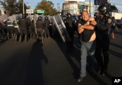 Police remove demonstrators who blocked a main road for about an hour during protests against gas price hikes in Mexico City, Jan. 4, 2017.