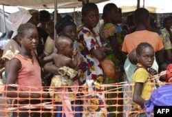 FILE - Internally-displaced people wait in line for medical attention at the Doctors Without Borders hospital based in the IDP camp near the international airport in Bangui, Dec. 23, 2013.
