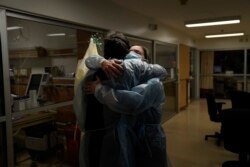 Chaplain Kevin Deegan, left, and registered nurse Michelle Stephens comfort each other in a COVID-19 unit at Providence Holy Cross Medical Center in the Mission Hills section of Los Angeles on Saturday, Jan. 9, 2021. (AP Photo/Jae C. Hong)