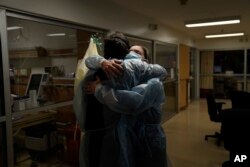 Chaplain Kevin Deegan, left, and registered nurse Michelle Stephens comfort each other in a COVID-19 unit at Providence Holy Cross Medical Center in the Mission Hills section of Los Angeles on Saturday, Jan. 9, 2021. (AP Photo/Jae C. Hong)