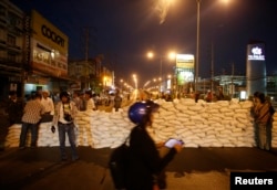 Anti-government protesters wait behind a barricade after closing the road near Government Complex in Bangkok, Thailand, Jan. 12, 2014.