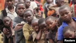 Des enfants réfugiés, déplacés par les conflits incessants dans la province du Nord-Kivu en RDC, attendent leur ration de nourriture à Nyakabande, un camp de transit de la ville de Kisoro en Ouganda, le 13 juillet 2012.