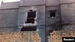 Men stand beside a damaged building near Mitiga airport in Libya's capital Tripoli, Nov. 25, 2014. 