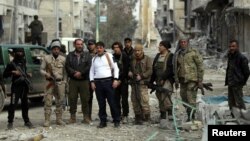 Rebel fighters pose for a picture in a damaged neighborhood in the northern Syrian town of al-Bab, Syria, March 4, 2017. 