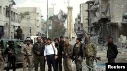 Rebel fighters pose for a picture in a damaged neighborhood in the northern Syrian town of al-Bab, Syria, March 4, 2017. 