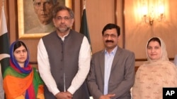 In this photo released by the Press Information Department, Pakistani Nobel Peace Prize winner Malala Yousafzai, left, and her parents pose for a photograph with Shahid Khaqan Abbasi, second from left, Prime Minister of Pakistan in Islamabad, Pakistan, Ma