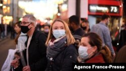 Shoppers, some wearing face coverings, cross Oxford Street in central London on Dec. 4, 2021, as compulsory mask wearing in shops has been reintroduced in England as fears rise over the Omicron variant of Covid-19. 