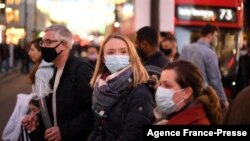 Shoppers, some wearing face coverings, cross Oxford Street in central London on Dec. 4, 2021, as compulsory mask wearing in shops has been reintroduced in England as fears rise over the Omicron variant of the coronavirus.