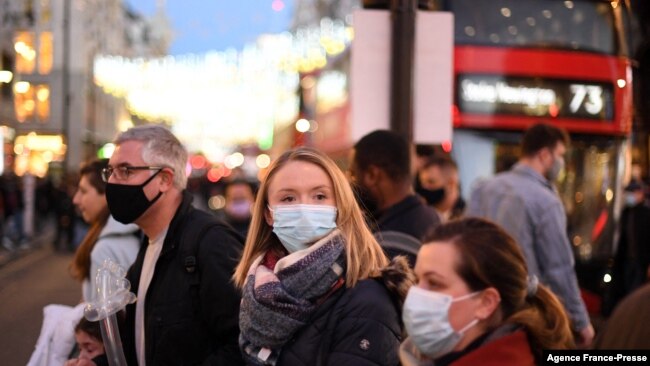 Shoppers, some wearing face coverings, cross Oxford Street in central London on Dec. 4, 2021, as compulsory mask wearing in shops has been reintroduced in England as fears rise over the Omicron variant of Covid-19.