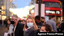 Orang-orang yang tengah berbelanjan di area London tengah tampak menggunakan masker saat menyeberang Oxford Street pada 4 Desember 2021. Inggris kembali memberlakukan wajib masker dalam upaya mencegah penyebaran varian baru COVID-19 omicron. (Foto: AFP/Daniel Leal)
