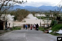 Residents stand by a flooded road following the onslaught of Typhoon Mangkhut in Tuguegarao city in Cagayan province, northeastern Philippines, Sept. 15, 2018.