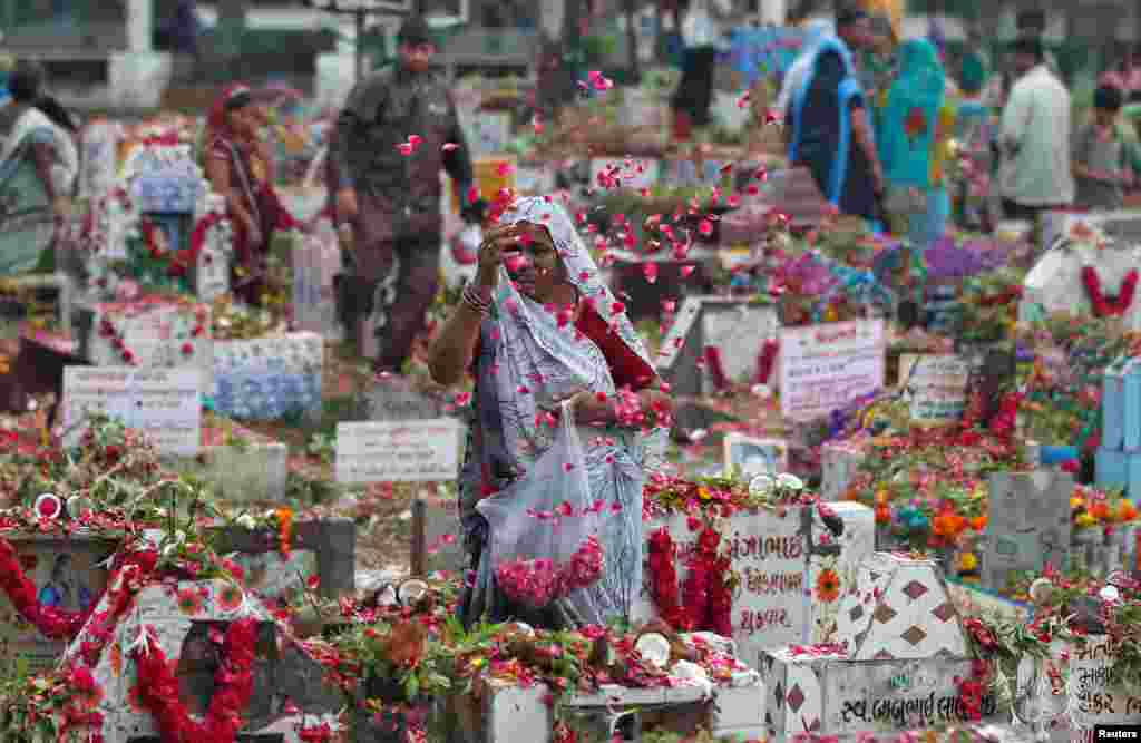 Uma mulher da tribo Devipujak atira pétalas de rosas em campa dos seus ente queridos, durante o festival Diwaso no qual as pessoas decoram campas, rezam e oferecem presentes aos seus ente queridos já falecidos. Ahmedabad, Índia, Julho 23, 2017.