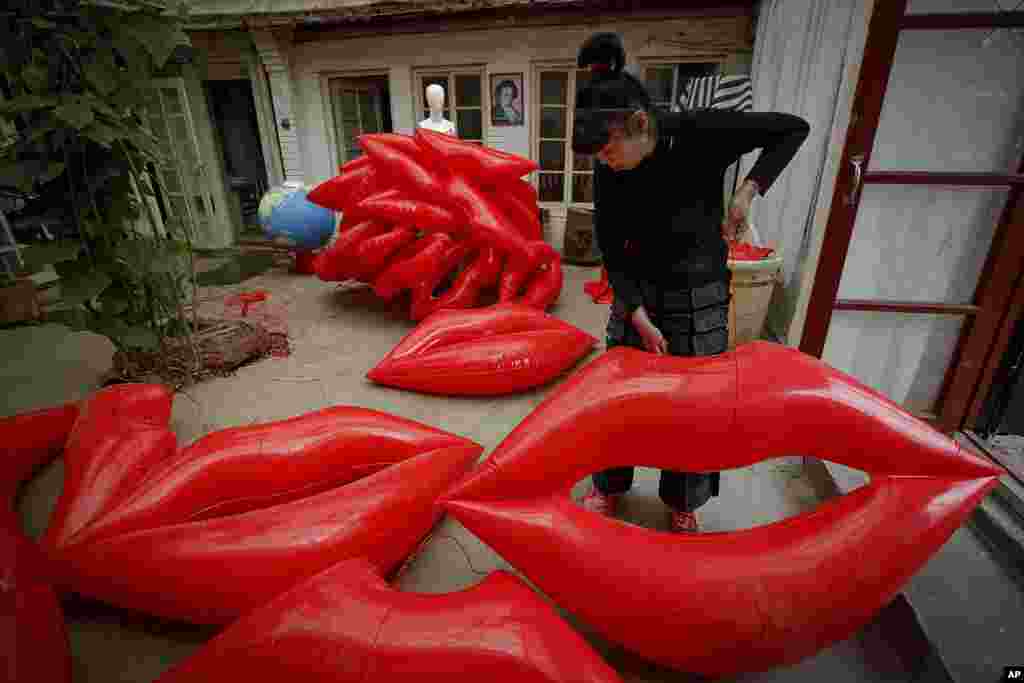 Artist and environmental activist Kong Ning prepares inflatable lip-shaped balloons with a theme &quot;Kiss the earth&quot; in support on Earth Day in Beijing, China.