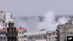 An amateur video released by the Shaam News Network purports to show smoke rising from buildings near a mosque in Homs, Syria, June 21, 2012.