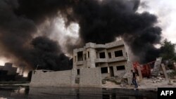 An Iraqi man walks near smoke billowing from oil wells, set ablaze by Islamic State militants before fleeing the oil-producing region of Qayyarah, Aug. 30, 2016.