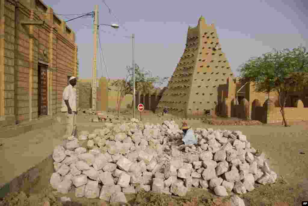 这张2012年5月1日拍摄的照片显示，两名男子在廷巴克图具有历史意义的土坯建成的清真寺附近工作。