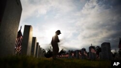 Lucille Williams walks through Georgia National Cemetery while visiting the grave of her late husband, Korean War veteran Sgt. 1st Class Alvin Williams, in honor of Memorial Day, May 25, 2015, in Canton, Ga. (AP Photo/David Goldman)