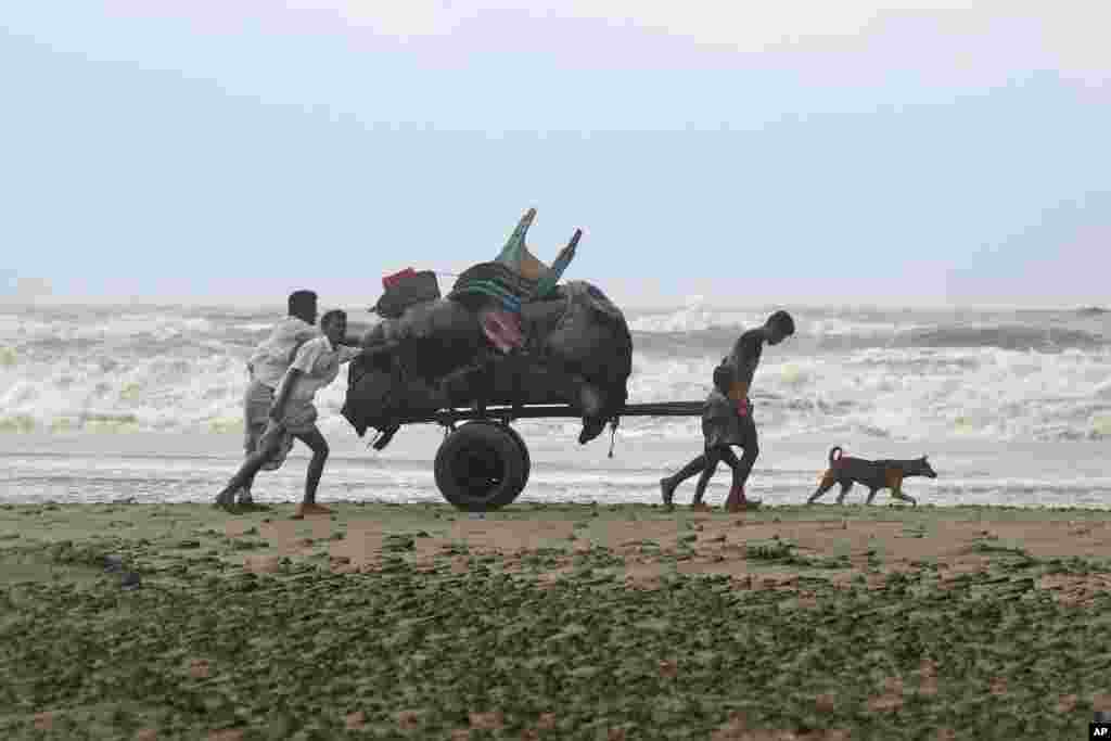 Bangladeshis push a cartload of belongings and walk back home after spending a night at a shelter in Cox&#39;s Bazar, Bangladesh. A tropical storm lashed southern Bangladesh, destroying hundreds of poorly built homes in some remote islands in the Bay of Bengal, officials said.