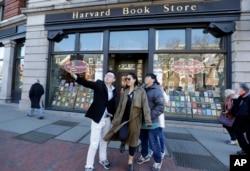 FILE - Students pose for a selfie outside the Harvard Book Store, March 9, 2017, in Cambridge, Mass. Readers have been flocking to classic works of dystopian fiction in the first months of Donald Trump's presidency.