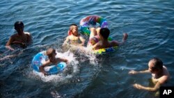 Children cool off on floating tube at Houhai Lake during summer heat in Beijing, July 28, 2013.