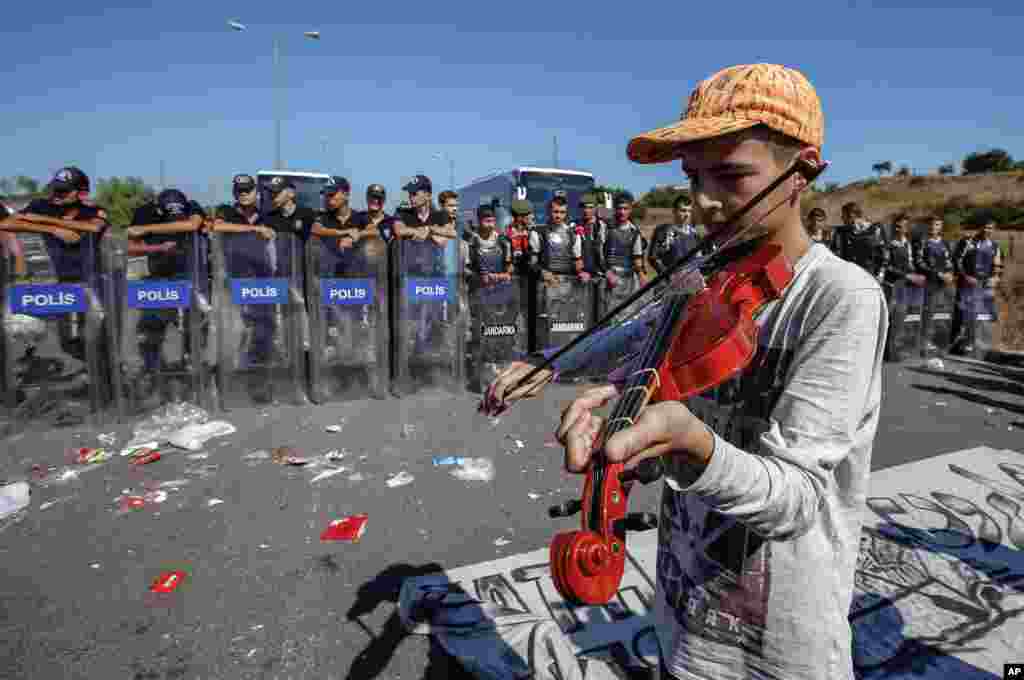 A refugee boy plays a violin as hundreds of migrants camp for a second day as they try to march down a highway towards Turkey&rsquo;s western border with Greece and Bulgaria, near Edirne, Turkey.