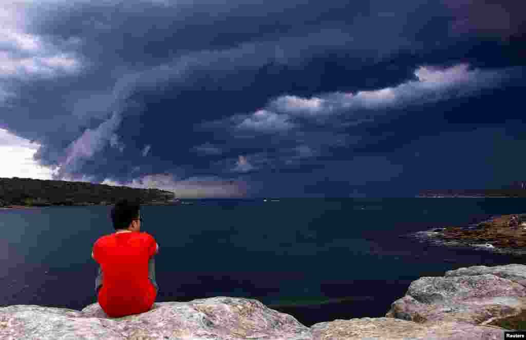 A Chinese tourist watches storm clouds moving along the coast towards the city of Sydney, Australia. Powerful storms swept across the city on Friday, with the Australian Bureau of Meteorology issuing a warning for severe thunderstorms with large hail, heavy rainfall and damaging winds.