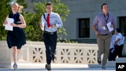 FILE - Interns run with a decision across the plaza of the Supreme Court in Washington, June 29, 2015.