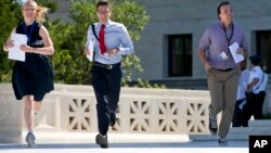 FILE - Interns run with a decision across the plaza of the Supreme Court in Washington, D.C., June 29, 2015. Some students in the U.S. defer college for a year, trying instead to gather life and work experiences in other environments.