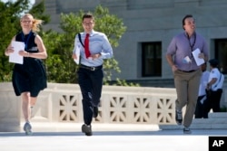 New interns run with a decision across the plaza of the U.S. Supreme Court in Washington on June 29, 2015. (Photo by Jacquelyn Martin/AP)